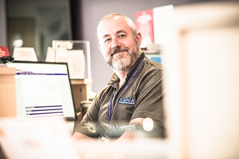 Picture of a smiling man at a reception desk
